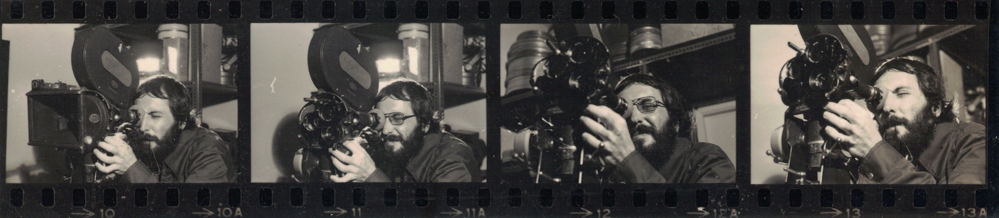 Trecho de negativo de imagem no qual Ramon Alvarado opera câmera cinematográfica e olha através de seu visor. Imagem preto e branco. Fotógrafo(a) não identificado(a).